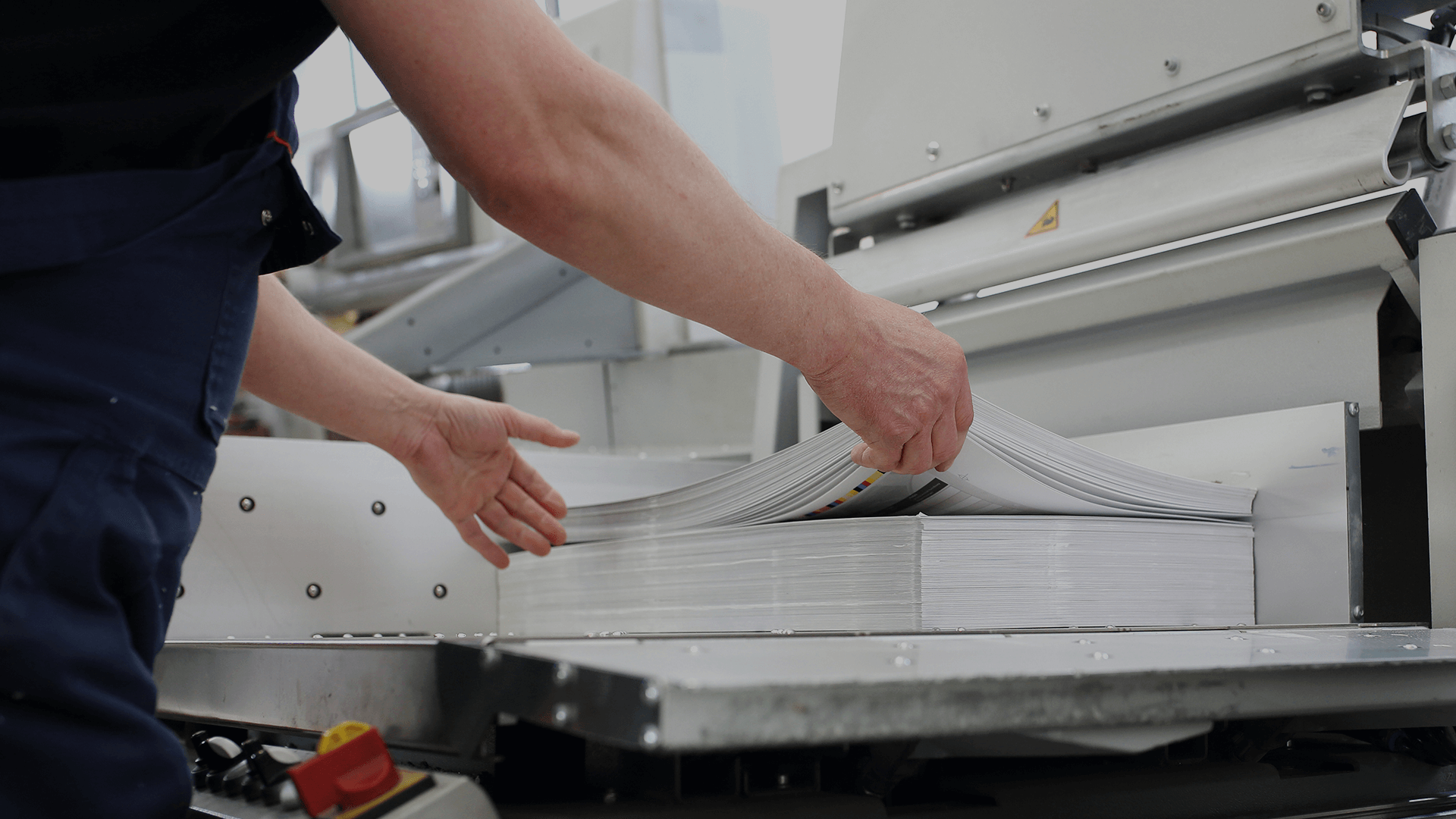 A set of hands picking up a stack of printed materials