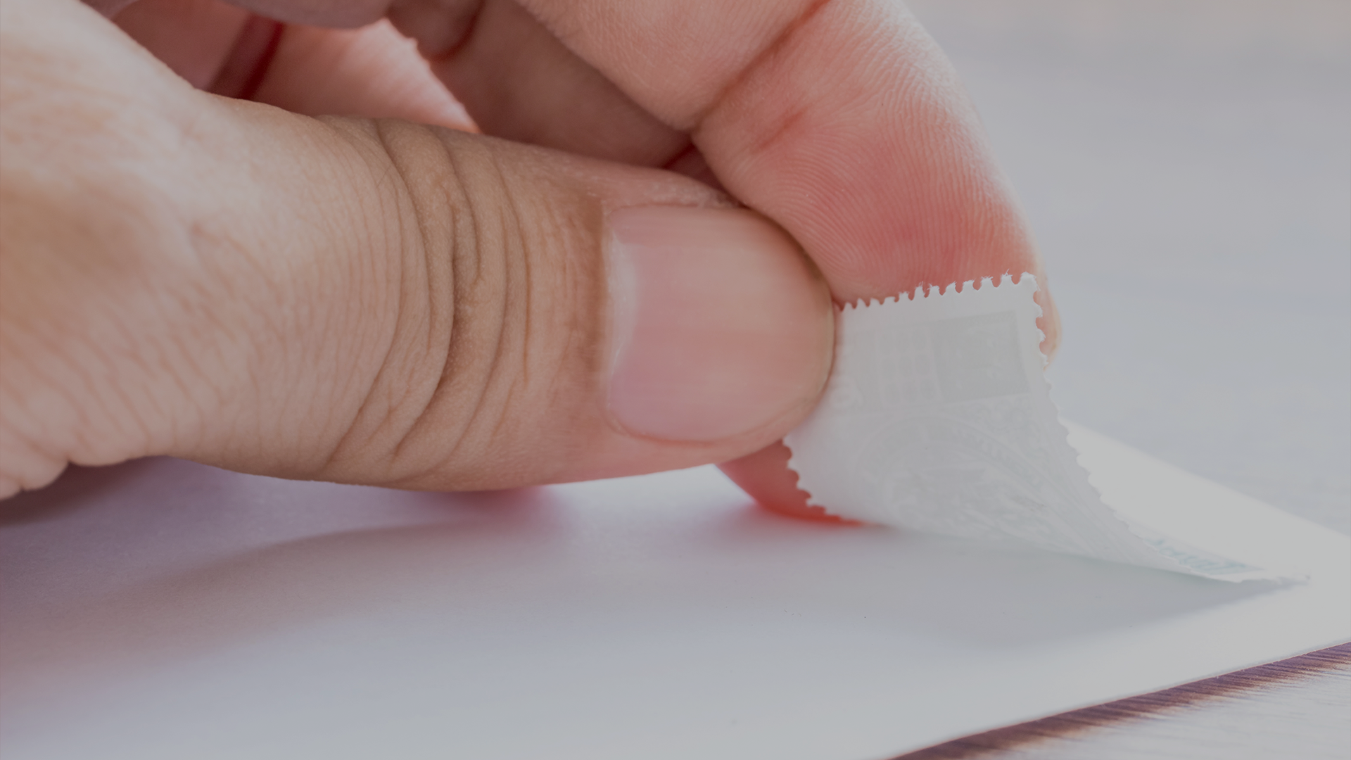 Human thumb holding corner of direct mailer