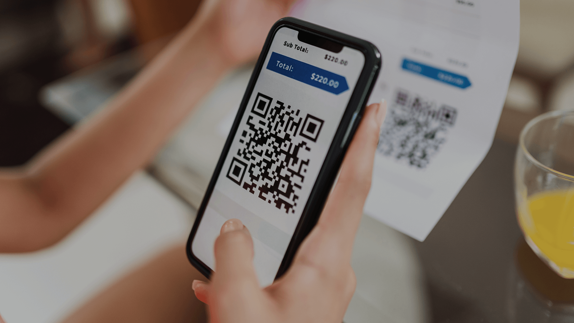 A hand holding a phone that has a QR code on the screen